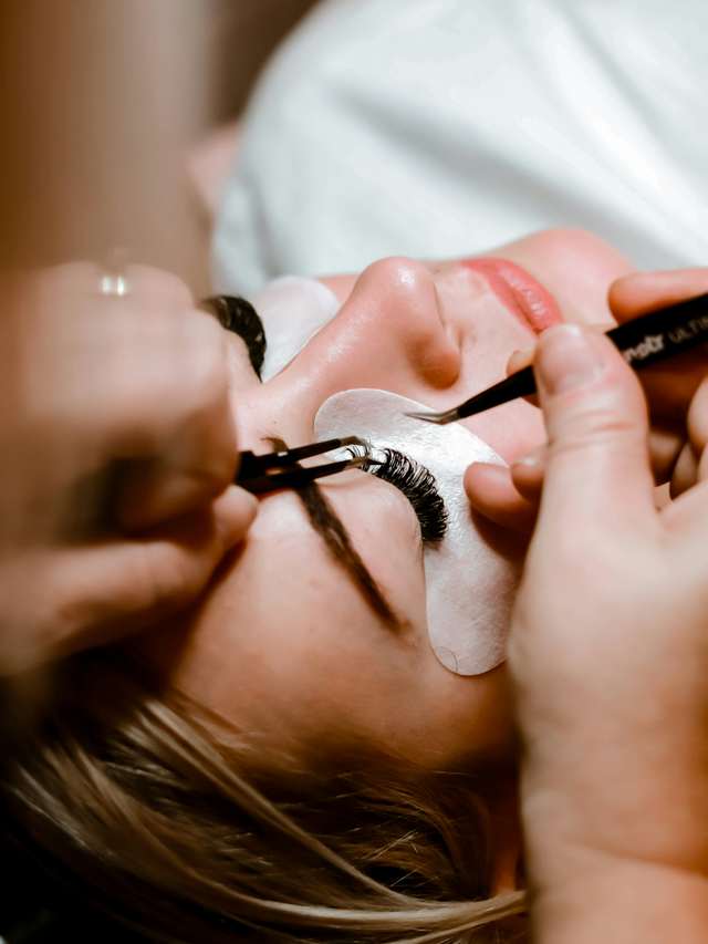 Wimpernstylistin setzt Extensions mit zwei Pinzetten